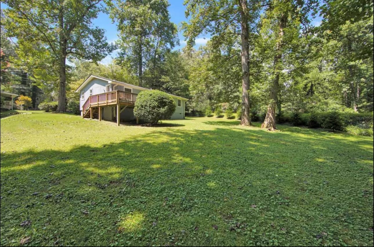 Backyard with mature trees, lawn, and rear deck